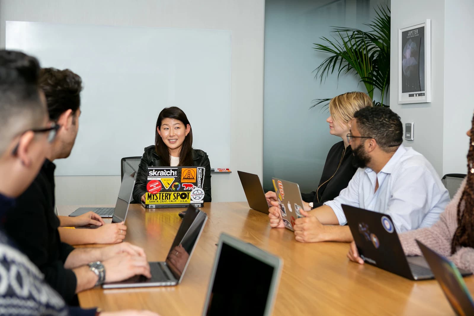 Colleagues in discussion around a table with laptops
