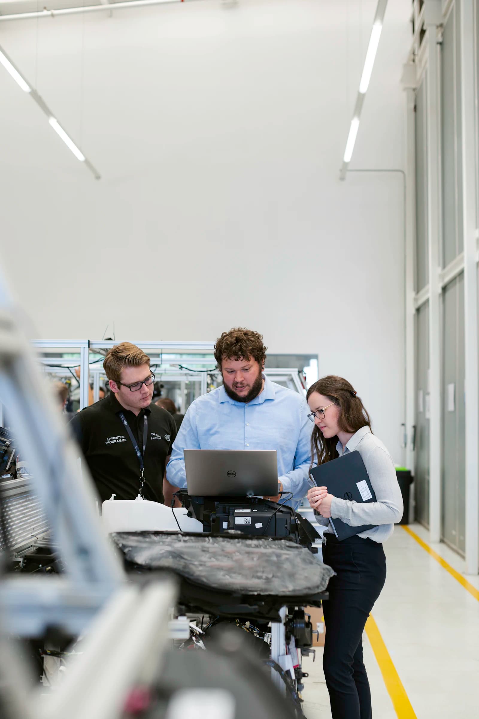 Three engineers reviewing results on a laptop in a lab