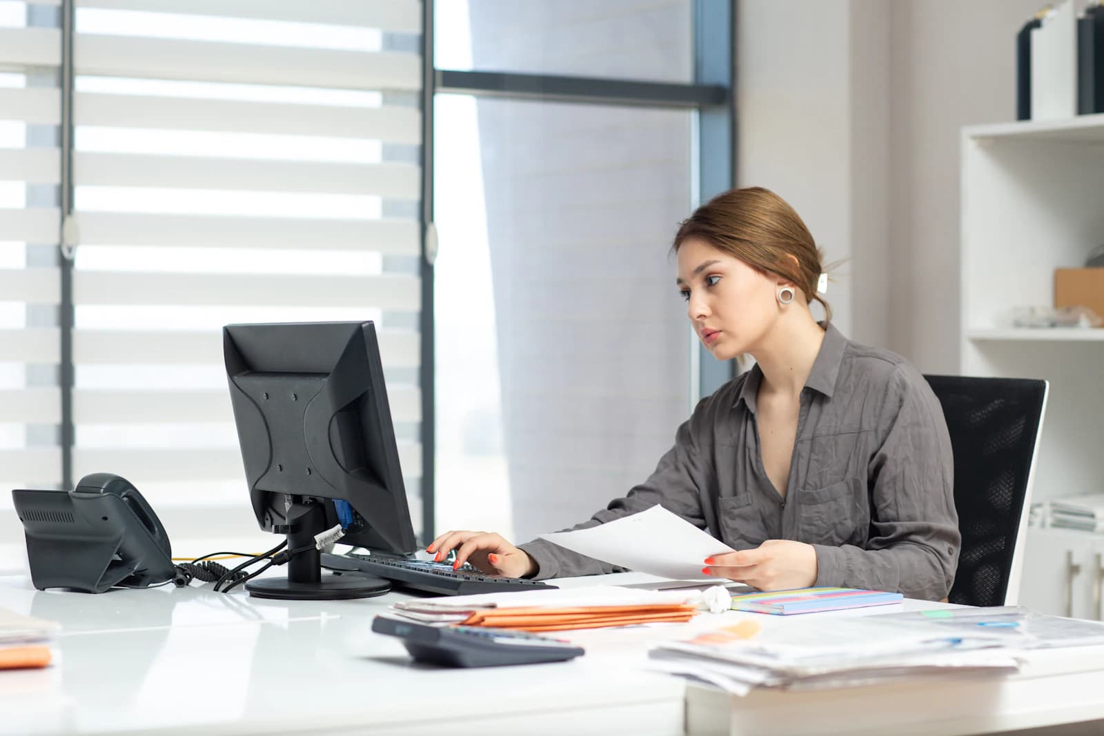 An office worker at her desk with a monitor and documents