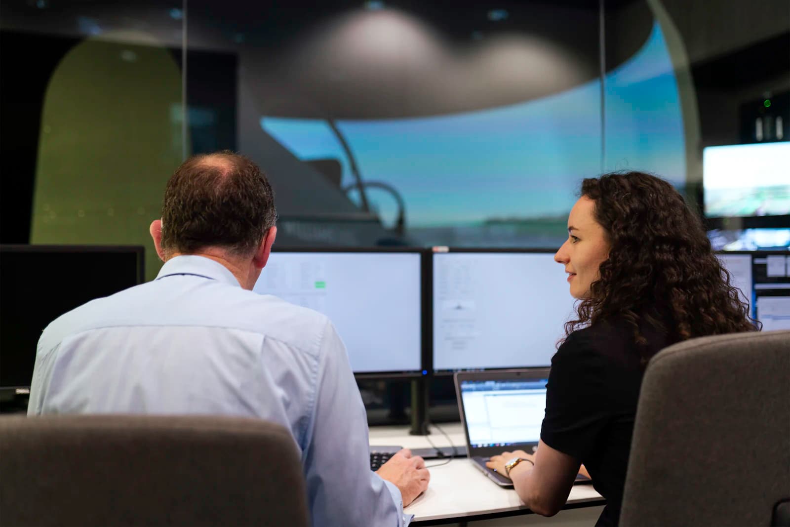 Two operators monitoring systems on several screens