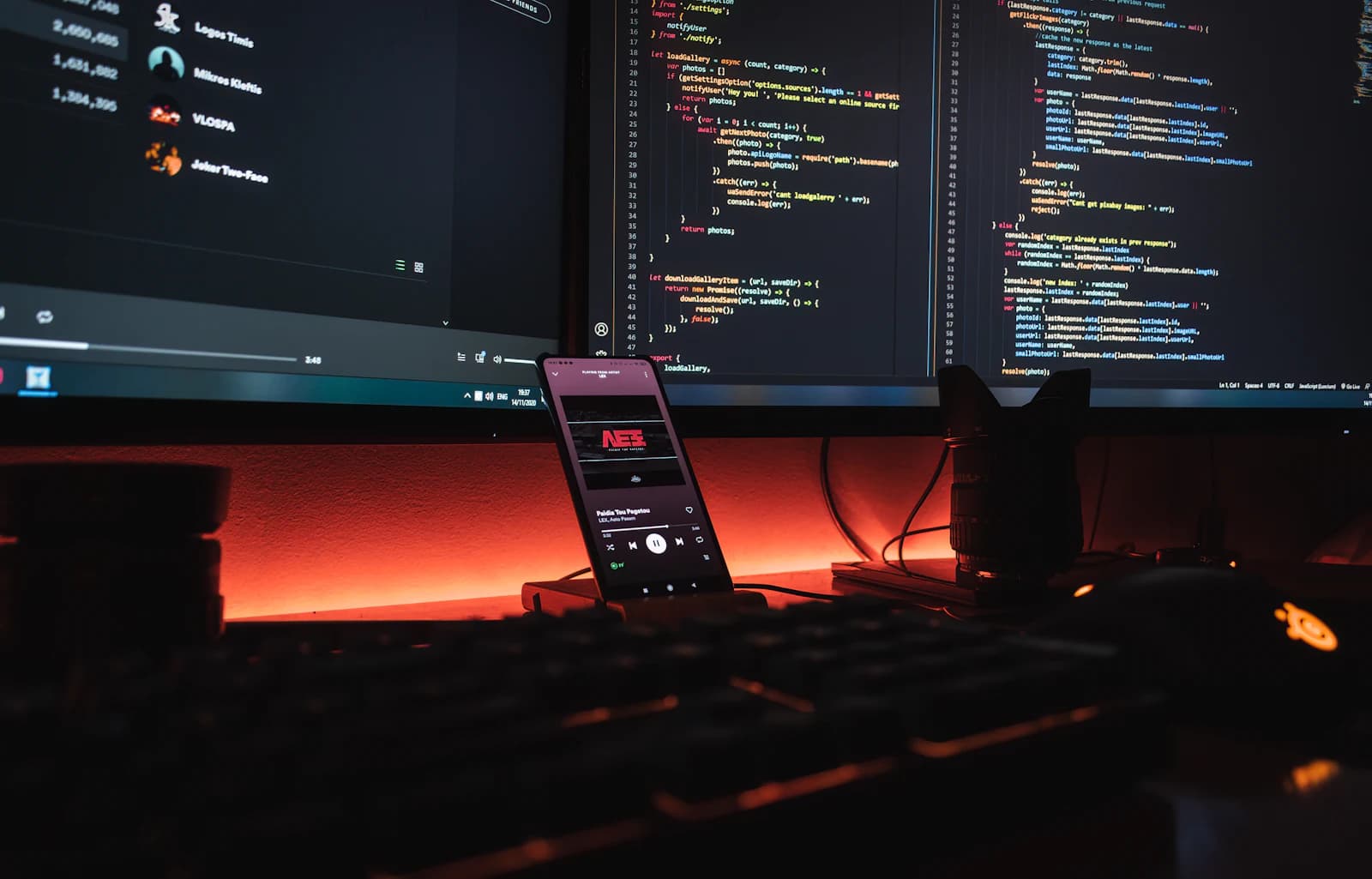 Monitors showing code, with a phone on the desk