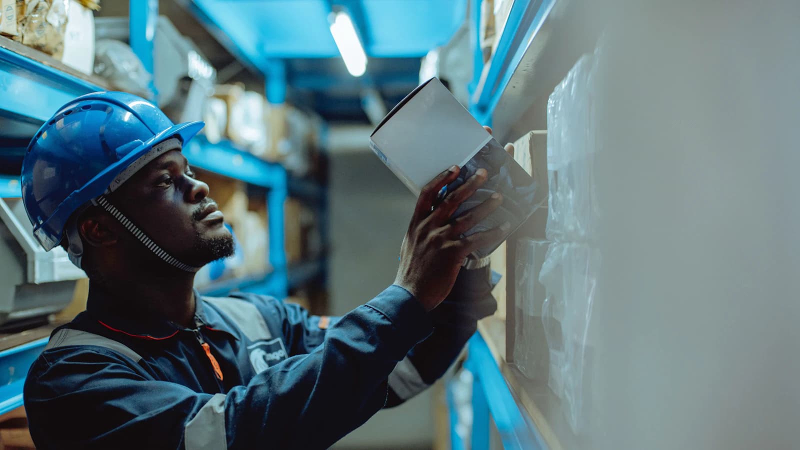 A warehouse worker using a tablet between the shelves
