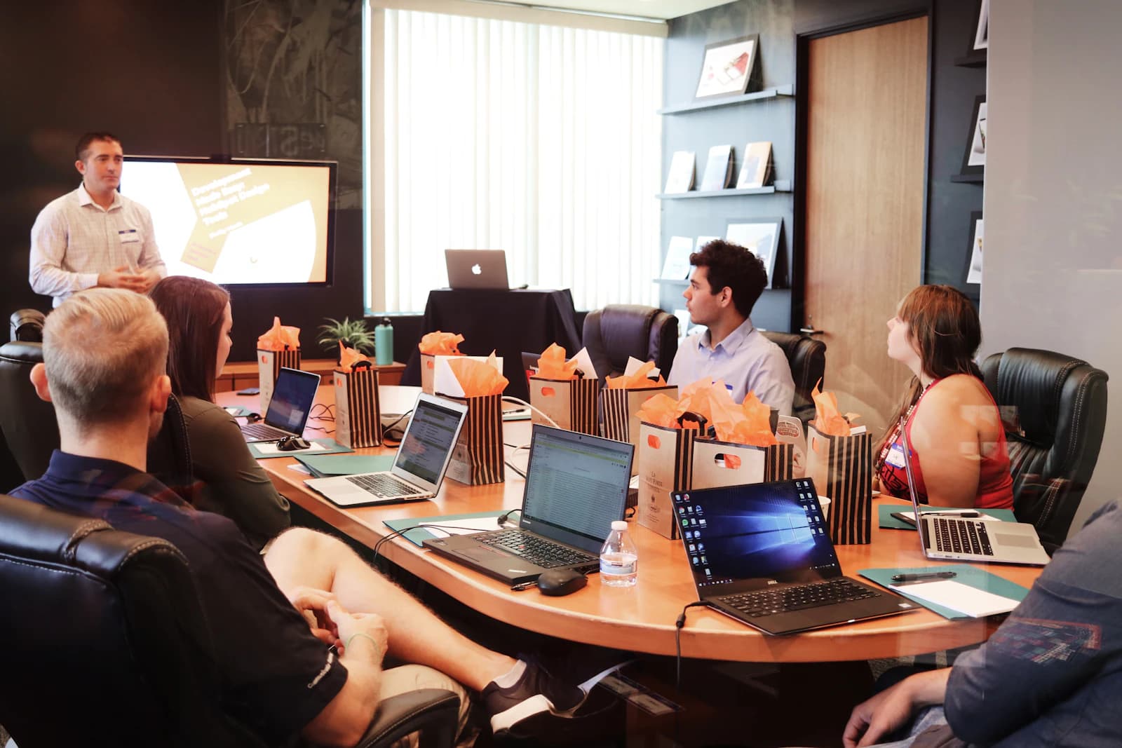 A presenter leading a working session with a team around laptops