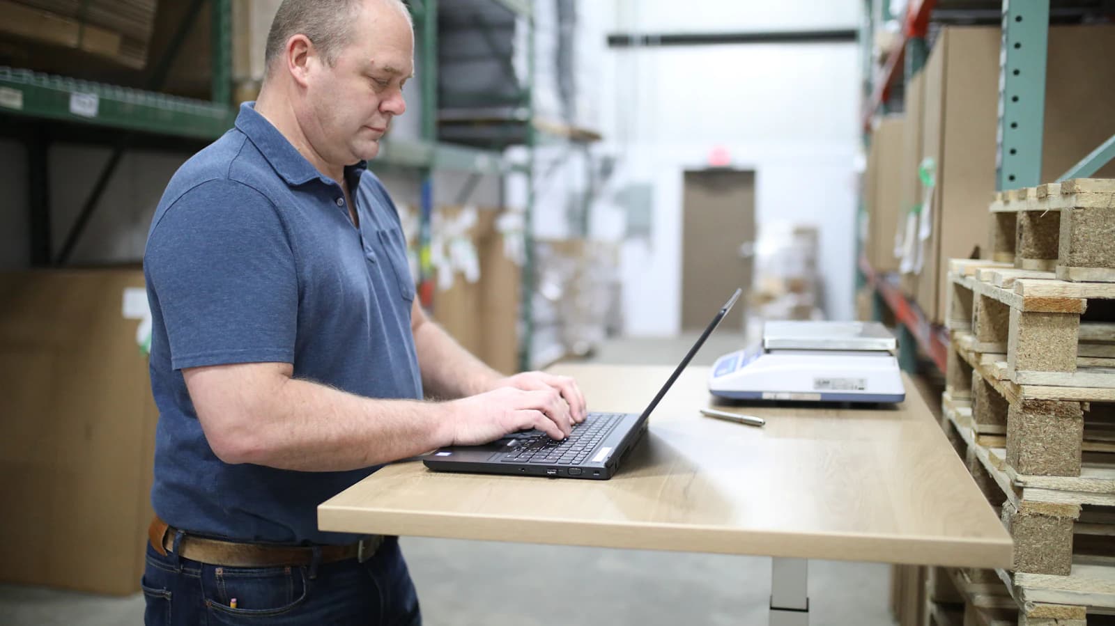 A manager working on a laptop in a warehouse