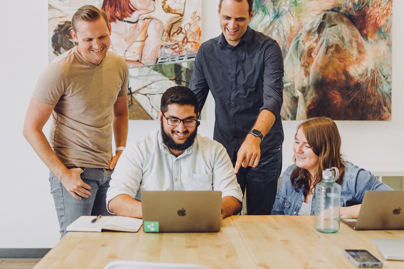 A team gathered around a laptop reviewing findings